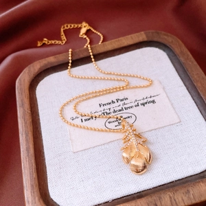 Detailed close-up of 18k gold plated feather pendant necklace with shimmering zircon stones
