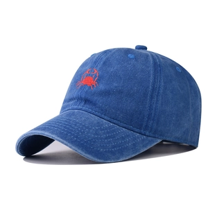 Macro shot of red crab embroidery on vintage washed denim blue cotton baseball cap