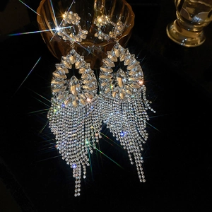 Close-up of luxury silver-tone tassel earrings with sparkling crystals on black background
