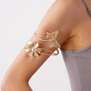 Dettaglio del bracciale da braccio dorato con farfalla e motivi floreali e strass lucidi