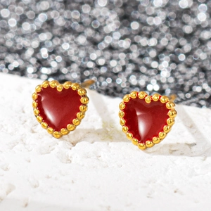 Gros plan de boucles d'oreilles cœur rouge avec bordure perlée dorée et émail élégant