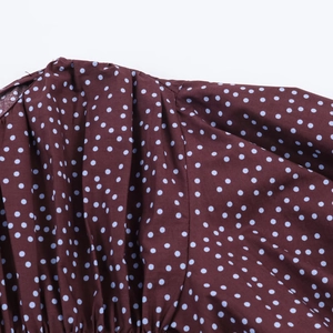 Detailed close-up of dark brown fabric with blue polka dots on a balloon sleeve shirt