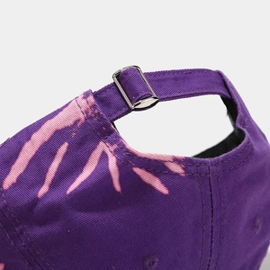 Vue détaillée de la boucle en métal réglable et de la texture tie-dye rose sur la casquette violette