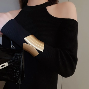 Detail of wide irregular gold cuff bracelet worn over a black sleeve in a luxury setting