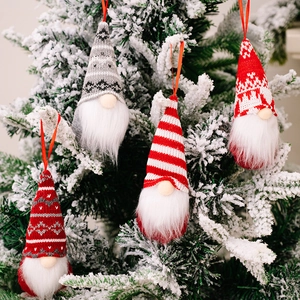 Detailed view of knitted Christmas gnome ornaments hanging on a snowy Christmas tree