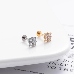 Detailed macro view of silver and golden G23 titanium flower labret studs with zircons