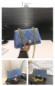 Detail of blue denim crossbody bag with diamond quilting and gold chain strap