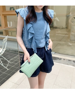 Detail of mint green crocodile pattern faux leather clutch bag with zipper closure
