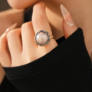 Detail view of a vintage gold-plated ring featuring a large purple pearl and pavé crystals