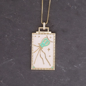 Detailed close-up of golden Aquarius square pendant with white enamel on grey stone
