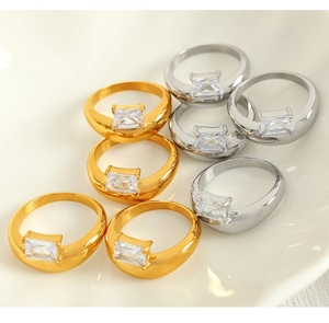 Assortment of gold and silver irregular rings with rectangular zircons in a ceramic bowl