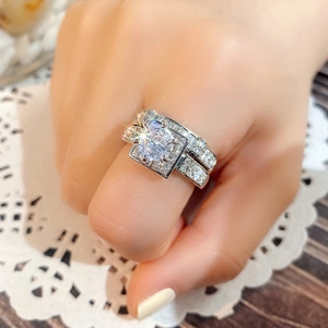Detailed view of silver square-cut bridal ring set worn on finger with lace background
