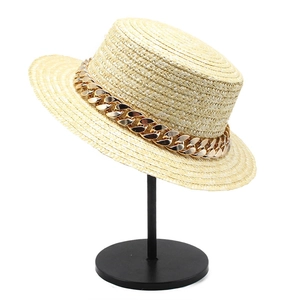 Chapeau de paille à sommet plat avec détail de chaîne dorée sur fond blanc neutre