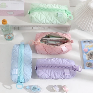 Quilted pastel pencil cases in mint, pink, blue, and purple on a tidy desk