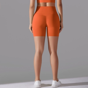 Detail view of high-waist orange yoga shorts showing seamless design and elastic fabric texture