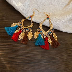 Detailed macro view of bohemian tassel earrings with gold leaf charms and colorful beads