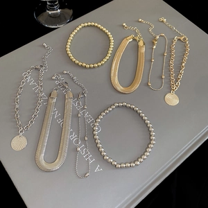 Dettaglio di bracciali a catena serpente oro e argento con ciondoli tondi su libro vintage