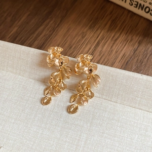 Macro shot of gold floral tassel earrings with layered petals and metallic luster