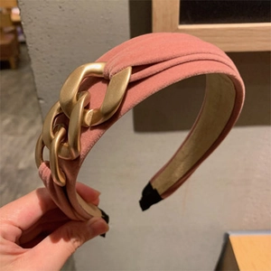 Close-up of pink velvet headband with elegant gold chain decoration held in hand