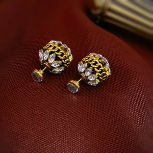 Détail de boucles d'oreilles boules dorées tressées avec zircons marquise blancs