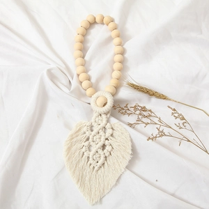 Detail of leaf-shaped cotton woven curtain tieback with natural wood beads decoration