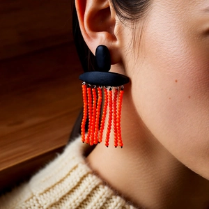 Close-up of ethnic style beaded tassel earrings in black and orange on a female model