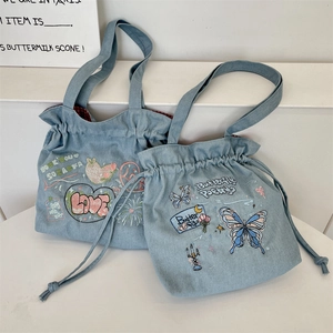 Detail of blue denim tote bag with colorful embroidery and red checkered lining