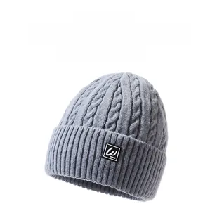 Detail of grey cable knit beanie showing thick wool texture and folded logo cuff