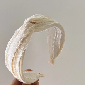 Close-up of cream knotted silk headband with frayed edge detail and soft texture