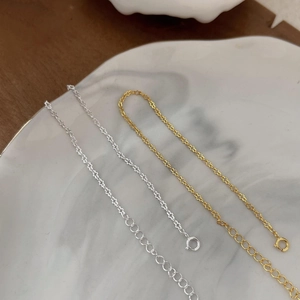Minimalist S925 sterling silver star-link bracelets in gold and silver on a white plate