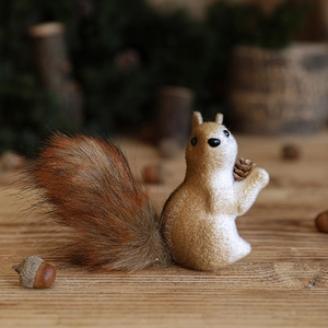 Brown flocked squirrel figurine holding a pine cone for festive Christmas tree decor