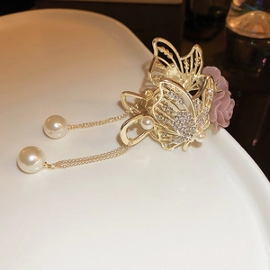 Close-up of golden butterfly hair claw with purple flowers, rhinestones and pearl tassels