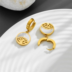 Detailed close-up of gold tree of life earrings with white shell inlay on a tray