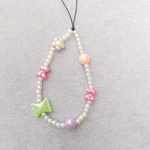 Detailed close-up of colorful beaded phone strap with pearls and resin flower charms