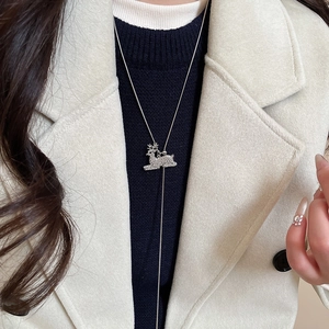 Close-up of a sparkling silver reindeer pendant with rhinestones on a sweater chain
