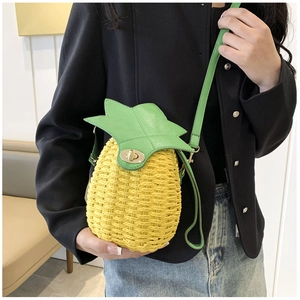 Close-up of handmade woven pineapple crossbody bag with green leaf flap and gold clasp