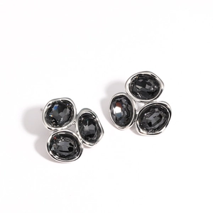 Dettaglio macro degli orecchini geometrici in zircone grigio scuro e metallo argento