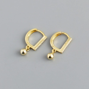Close-up of gold hoop earrings with small cubic zirconia inlays and ball pendants