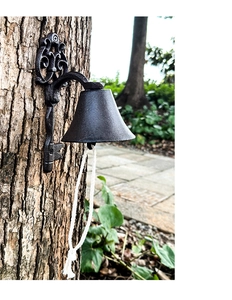 Close-up of vintage cast iron door bell with scrolling leaf patterns and white pull rope