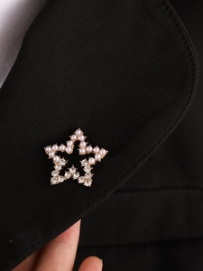 Detailed close-up of a star brooch with pearls and rhinestones on a black suit lapel