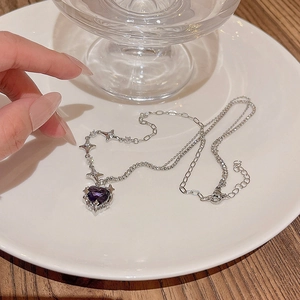 Macro detail of silver necklace with purple heart gemstone pendant and mixed link chains