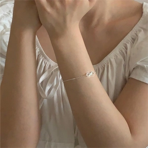 Macro shot of minimalist silver infinity charm bracelet on woman's wrist