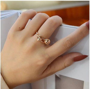 Close-up of dual ball rose gold ring on hand with polished mirror finish detail