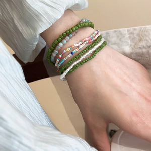Detail of bohemian seven-piece colorful bead bracelet set worn on a model's wrist