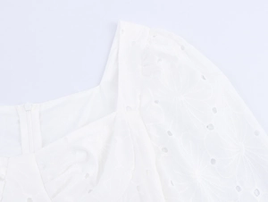 Détail de l'encolure carrée et de la broderie anglaise sur une robe d'été blanche