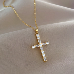 Close-up of gold-plated cross pendant with shimmering inlaid crystals on silk background