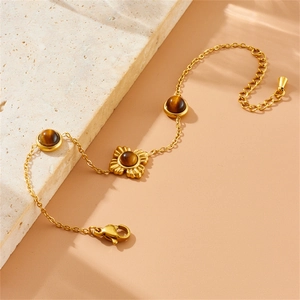 Golden tiger eye stone flower bracelet set with lobster clasp on a beige marble block