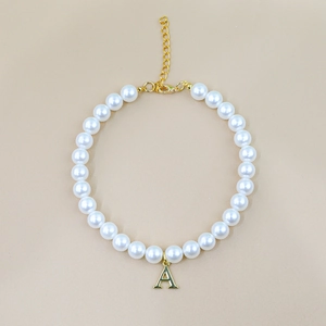 Detailed macro view of white pearl pet necklace featuring a golden letter A pendant