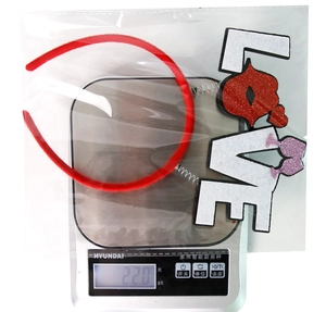 Detail view of a LOVE headband with red lips and glitter on a digital scale for weight check