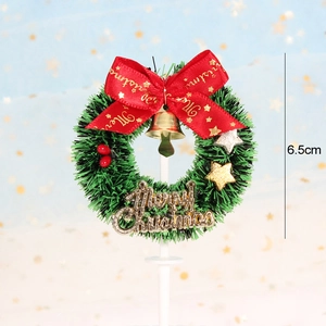 Detailed view of a 6.5cm mini green Christmas wreath cake topper with red bow and gold bell